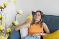 Unhappy young caucasian blonde woman relaxing at home alone, sitting on couch in comfortable pose, blogger sharing good Royalty Free Stock Photo