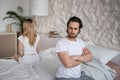 Unhappy young couple having relationship problems, sitting on opposite sides of bed, not looking at each other at home Royalty Free Stock Photo