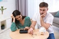 Unhappy young couple with piggy bank and money. Financial problems