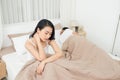 Unhappy Young Couple Sitting On Bed In Bedroom Royalty Free Stock Photo
