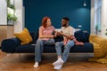 Unhappy young diverse married couple sitting on sofa talking about problems in relationship Royalty Free Stock Photo