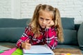 Unhappy young elementary student schoolgirl studying and doing homework at home Royalty Free Stock Photo