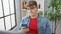 Unhappy young hispanic man at the office job, a struggling business worker typing on his smartphone, upset amid success Royalty Free Stock Photo