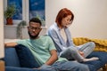 Unhappy young interracial couple sit separately on sofa at home not talking after fight Royalty Free Stock Photo