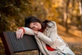 Unhappy young woman in casual clothes sitting on bench at autumn park Royalty Free Stock Photo