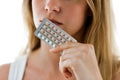 Unhappy young woman holding contraceptive pills over white background. Royalty Free Stock Photo