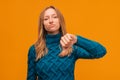 Unhappy Young woman showing a thumb down. Unlike, dislike, failure gestures concept. Studio shot, yellow background Royalty Free Stock Photo