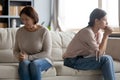 Unhappy young woman and mature mother avoiding talking after quarrel