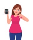 Unhappy young woman showing, holding calculator and gesturing thumbs down sign. Modern trendy girl making dislike, bad or negative