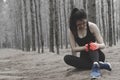 Unhappy young woman sitting in the garden, grabbing an ankle, un