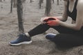 Unhappy young woman sitting in the garden, grabbing an ankle, un Royalty Free Stock Photo