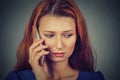 Unhappy young woman talking on mobile phone looking down Royalty Free Stock Photo