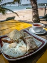 Unhealthy breakfast on the sunny beach. Fried eggs with sausage and bread