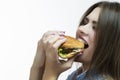 Unhealthy Eating Concepts. Closeup of Caucasian Woman Eating Burger. Profile Face View. Posing in Striped Shirt Indoors in Studio