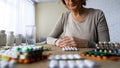 Unhealthy elderly lady suffering pain looking at pills, painkillers hypochondria