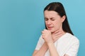 Unhealthy female standing isolated over blue background covers her mouth with hand while coughing, suffers from seasonal grippe or Royalty Free Stock Photo