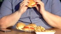 Unhealthy food addiction, obese hungry man eating fatty burgers, overweight