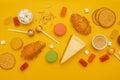 Unhealthy foods on a colored background, top view. French croissant, candy on a stick, jelly candies, marshmallows Royalty Free Stock Photo