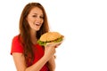 Unhealthy meal - happy young woman eats hamburger isolated over