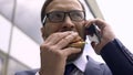 Unhealthy nutrition, busy businessman talking on phone and eating burger lunch Royalty Free Stock Photo
