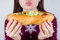 Unhealthy nutrition concept. Cropped close up photo of satisfied dreamy lady holding in hands long loaf bread in hands stuffed