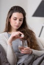 Unhealthy sick woman takes pill with glass of water