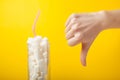 Unhealthy sugar content in drinks. Gesture of a hand with a finger down on a yellow background