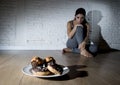 Unhealthy sugar donuts and muffins and tempted young woman or te Royalty Free Stock Photo