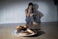 Unhealthy sugar donuts and muffins and tempted young woman or teenager girl sitting on ground