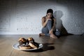 Unhealthy sugar donuts and muffins and tempted young woman or teenager girl sitting on ground