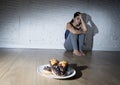 Unhealthy sugar donuts and muffins and tempted young woman or teenager girl sitting on ground