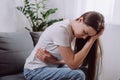 Unhealthy upset young woman suffering from menstrual pain. Sad girl with hand squeezing belly having painful stomach ache or Royalty Free Stock Photo