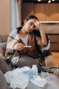 Unhealthy woman sit in blanket hat feel sick suffer from flu or covid-19 corona virus. Unwell young female sneeze sniffle have Royalty Free Stock Photo