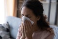 Unhealthy young lady using paper tissue, wiping runny nose.