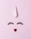 Unicorn face made of seashell with eyelashes on pastel pink background. Summer minimal concept