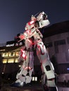 Unicorn Gundam standing in front of the Diver City Tokyo Plaza at Odaiba city night