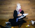 Unicorn in a suit and tie on wooden background in home office works with the documents.