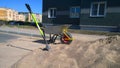 Unicycle wheelbarrow with one wheel, shovel, pile of sand near residential building. City street. Construction site. Road works.