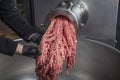 Unidentifiable butcher holding tray full of minced raw red meat leaving machine in food processing plant