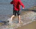 An unidentifiable child runs along the seashore in bare feet, sp Royalty Free Stock Photo