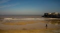 Unidentifiable couple dog walking on Cromer beach on the North Norfolk coast Royalty Free Stock Photo