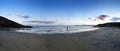 Unidentifiable man fishing on the beach at twilight in hemmick bay near gorran haven in cornwall just after sunset with blue