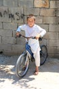 Unidentified Afghan Boy with bicycle standing and posing in front of his house