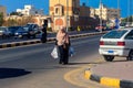 Unidentified arabic muslim woman in hijab crossing the road with shopping bags in hands