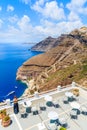 Unidentified attractive woman in stylish dress standing on a terrace and looking at beautiful caldera and sea, Firostefani villa Royalty Free Stock Photo