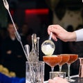 Unidentified barman adding foam in a martini glass with cocktail
