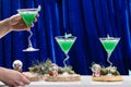 Unidentified barman holding martini glass with Christmas cocktail on blue background