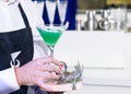 Unidentified barman holding a martini glass with green alcoholic