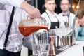 Unidentified barman pouring juice in a metal glass