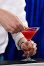 Unidentified barman preparing cocktai blue background